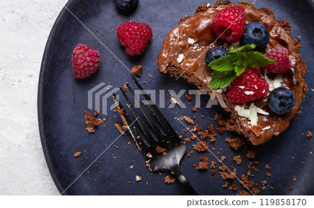 half-eaten chocolate tartlet, on a plate, stuffed with cottage cheese and berries, breakfast, homemade, no people, 119858170