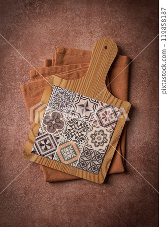 wooden cutting board with ceramic tiles, on a kitchen towel, top view, food background, 119858187