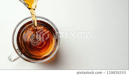Black tea is pouring into glass mug, top view, tea package design element, white background with copy space for your ad text 119858333