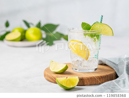 Mojito cocktail or tonic with lemon, lime, mint and ice on a wooden board.  119858368