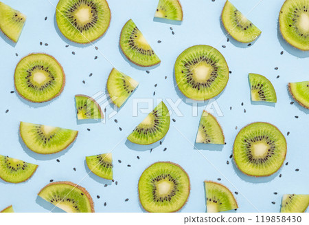 Pattern of juicy slices of kiwi fruits and seeds on a blue background with shadow. Pattern of juicy slices of kiwi fruits and seeds on a blue background with shadow. 119858430