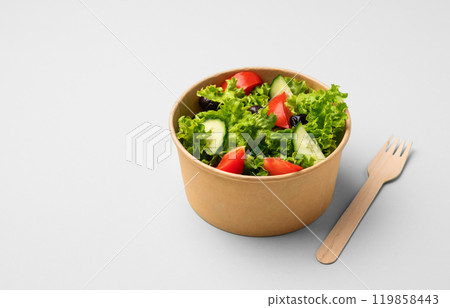 Fresh salad in eco-friendly container with wooden fork on light background. 119858443