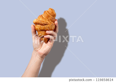 Hand hold fresh croissant on a gray background. Design concept for breakfast pastry mockup or banner Hand hold fresh croissant on a gray background. Design concept for breakfast pastry mockup or banner 119858614
