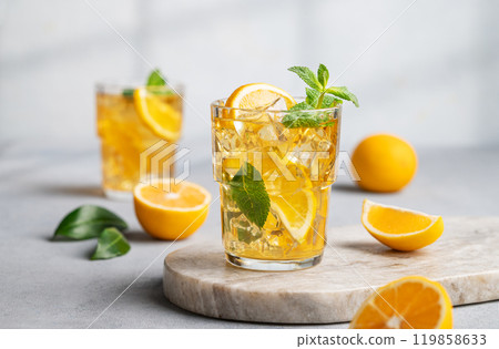 Two glasses with iced drink with lemon and mint on a marble board on a light background with shadow  119858633
