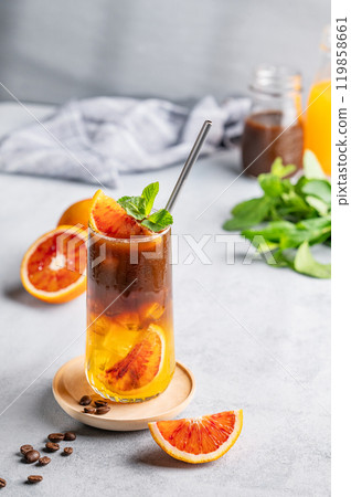 Espresso coffee with orange juice (bumble) in a tall glass with ice and mint on a blue background 119858661