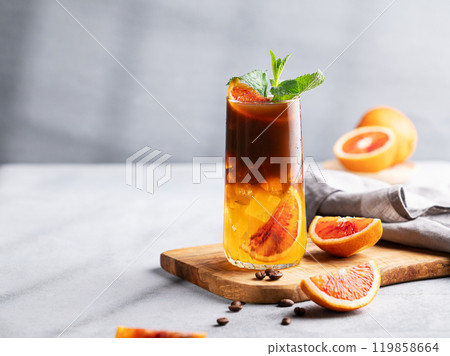 Coffee with orange juice (bumble) in a tall glass with ice and mint on a wooden board Coffee with orange juice (bumble) in a tall glass with ice and mint on a wooden board 119858664