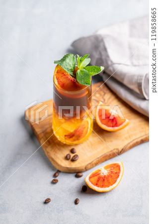 Coffee with orange juice (bumble) in a tall glass with ice and mint on a wooden board Coffee with orange juice (bumble) in a tall glass with ice and mint on a wooden board 119858665
