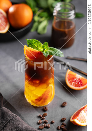 Coffee with orange juice (bumble) in a tall glass with ice and mint on a dark background 119858668