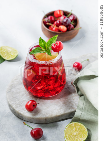 Cherry-lime mojito cocktail with mint, lime and ice on a marble  board on a light background  119858685