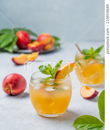 Two glasses with peach cocktail, lemonade or iced tea on a light background. Two glasses with peach cocktail, lemonade or iced tea on a light background. 119858689