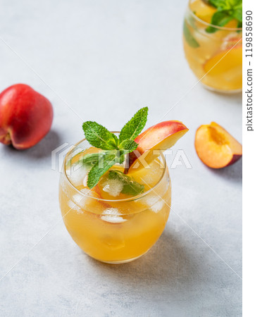 Refreshing peach cocktail, lemonade or iced tea in a glass on a light background. Refreshing peach cocktail, lemonade or iced tea in a glass on a light background. 119858690