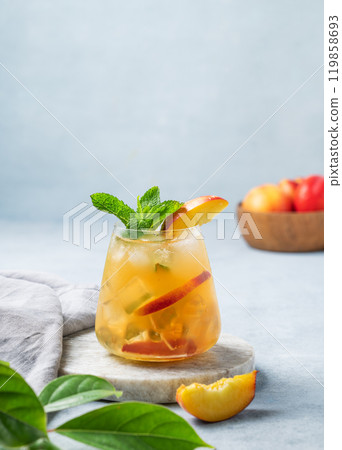 Refreshing peach cocktail, lemonade or iced tea on a marble board on a light background with leaf. Refreshing peach cocktail, lemonade or iced tea on a marble board on a light background with leaf. 119858693
