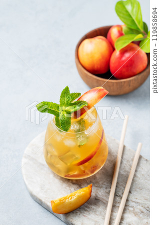 Refreshing peach cocktail, lemonade or iced tea on a marble board with tube on a light background. Refreshing peach cocktail, lemonade or iced tea on a marble board with tube on a light background. 119858694