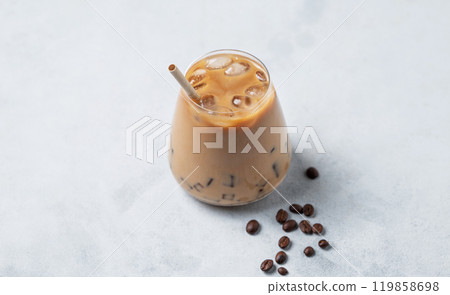 Iced coffee latte in a glass with milk on a light background with coffee beans. 119858698