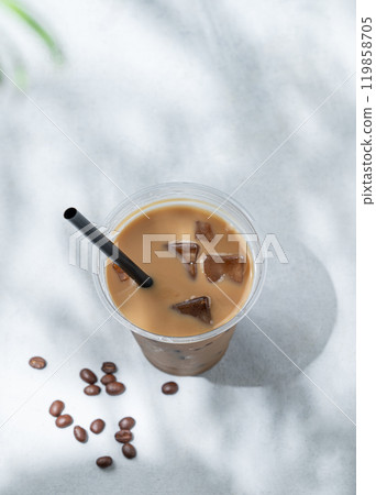 Iced coffee latte in a recyclable plastic glass with milk and ice on a light background  119858705