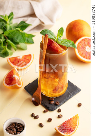 Espresso coffee with orange juice (bumble) in a tall glass with ice and mint on a yellow background Espresso coffee with orange juice (bumble) in a tall glass with ice and mint on a yellow background 119858743