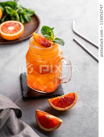Freshly squeezed blood orange juice with ice, mint and a slice of fruit on a blue background Freshly squeezed blood orange juice with ice, mint and a slice of fruit on a blue background 119858747