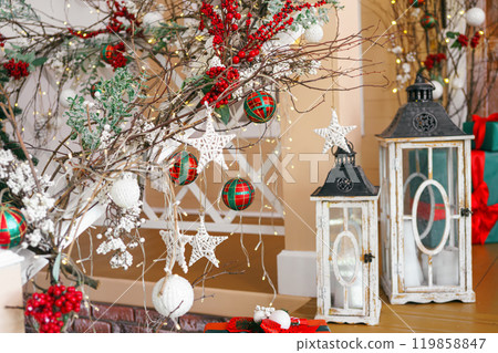 Festive holiday decorations, branches, ornaments and lanterns in cozy winter setting for Christmas Festive holiday decorations, branches, ornaments and lanterns in cozy winter setting for Christmas 119858847