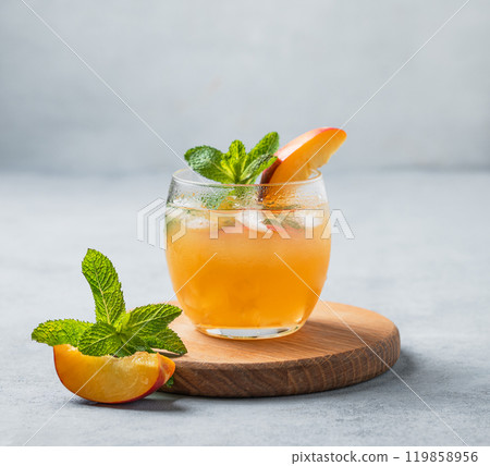 Refreshing peach cocktail, lemonade or iced tea on a wooden board on a light background. 119858956