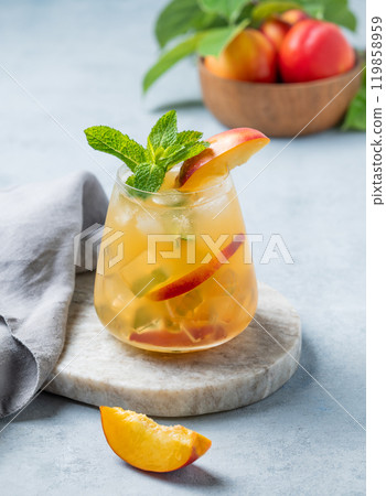 Refreshing peach cocktail, lemonade or iced tea in a glaa on a marble board on a light background. Refreshing peach cocktail, lemonade or iced tea in a glaa on a marble board on a light background. 119858959