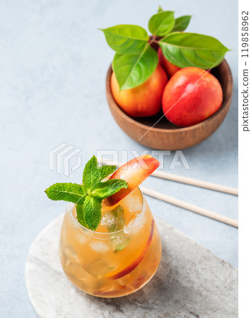 Refreshing peach cocktail, lemonade or iced tea on a marble board with tube on a light background. Refreshing peach cocktail, lemonade or iced tea on a marble board with tube on a light background. 119858962