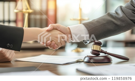 Two individuals engage in a firm handshake, symbolizing a successful agreement in a legal office filled with documents and professional decor Two individuals engage in a firm handshake, symbolizing a successful agreement in a legal office filled with documents and professional decor 119858976