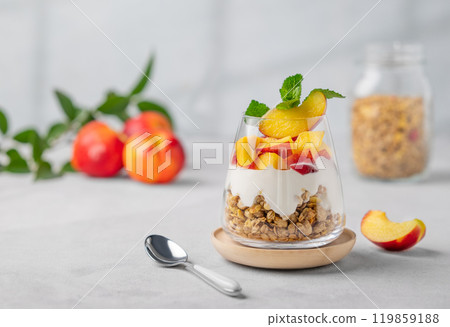 Greek yogurt parfait with peach and granola in a glass on a light background with fresh fruits Greek yogurt parfait with peach and granola in a glass on a light background with fresh fruits 119859188