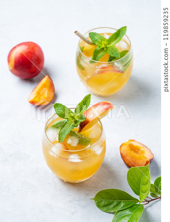 Two glasses with refreshing peach cocktail, lemonade or iced tea on a light background. Two glasses with refreshing peach cocktail, lemonade or iced tea on a light background. 119859235