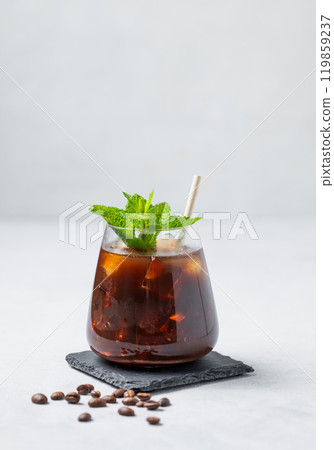 Ice coffee espresso in a glass with mint and ice on a black board on a light background Ice coffee espresso in a glass with mint and ice on a black board on a light background 119859237