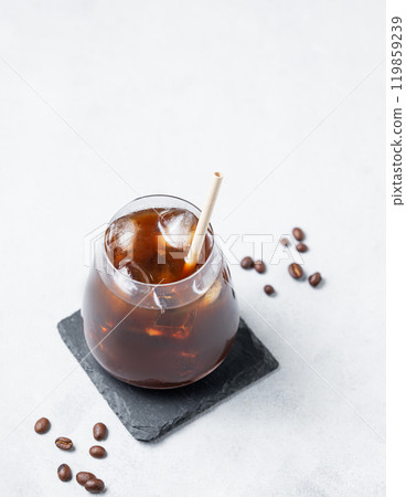 Coffee espresso in a glass with ice on a black board on a light background with coffee beans. 119859239