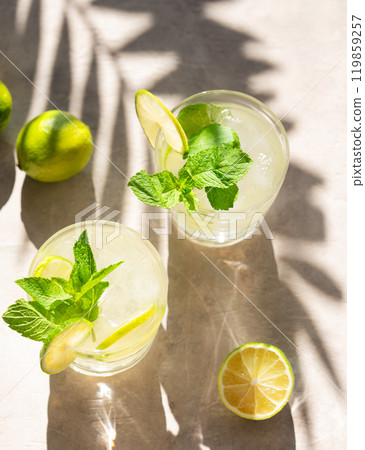 Two glasses with lime lemonade with mint and ice. Refreshing mojito cocktail with citrus fruits Two glasses with lime lemonade with mint and ice. Refreshing mojito cocktail with citrus fruits 119859257