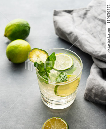 lime mojito with mint and ice in a glass. Refreshing citrus cocktail on a light background lime mojito with mint and ice in a glass. Refreshing citrus cocktail on a light background 119859271