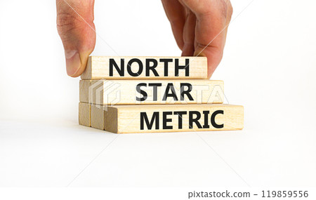 North star metric symbol. Concept words North star metric on wooden blocks on a beautiful white table white background. Businessman hand. Business finacial and north star metric concept. Copy space. 119859556