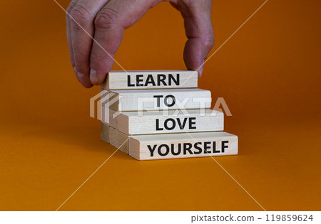 Learn to love yourself symbol. Concept words 'Learn to love yourself ' on wooden blocks on a beautiful orange background. Businessman hand. Business, psychological and learn to love yourself concept. 119859624