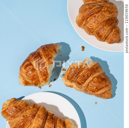Flat lay of  fresh croissants on blue background with shadow.  119859656