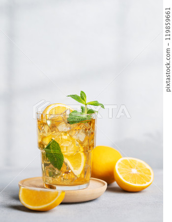 Iced drink with lemon, mint in a glass on a on a light background with shadow and citrus fruits. 119859661