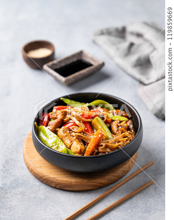 Stir-fry with soba noodles, meat and vegetables on a light background with chopsticks, soy sauce Stir-fry with soba noodles, meat and vegetables on a light background with chopsticks, soy sauce 119859669