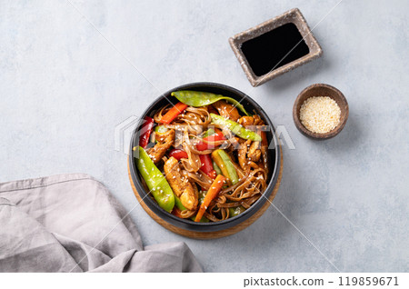 Stir-fry with soba noodles, meat and vegetables on a light background.  119859671
