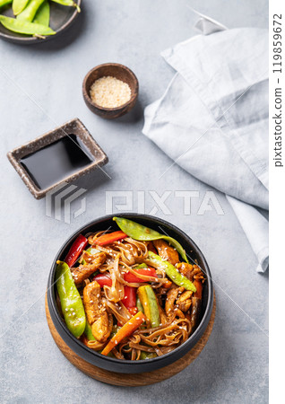 Stir-fry with soba noodles, meat and vegetables on a light background.  119859672
