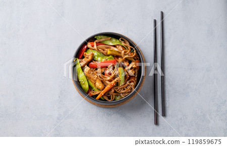 Stir-fry with soba noodles, meat and vegetables in black plate on a light background. Stir-fry with soba noodles, meat and vegetables in black plate on a light background. 119859675
