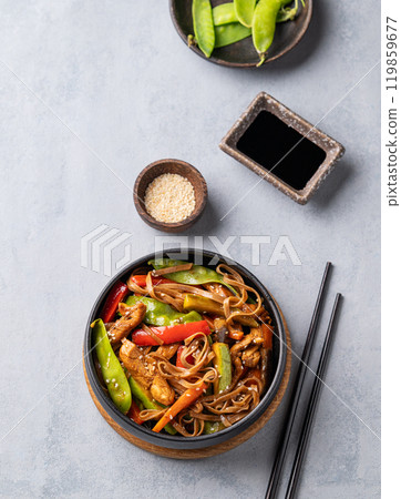Stir-fry with soba noodles, meat and vegetables on a light background.  119859677
