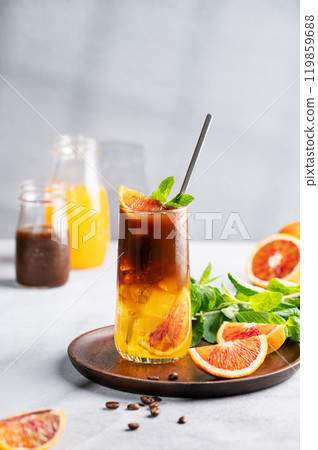 Coffee with orange juice (bumble) in a tall glass with ice and mint on a wooden plate  119859688