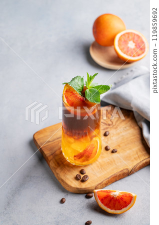 Coffee with orange juice (bumble) in a tall glass with ice and mint on a wooden board  119859692