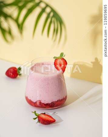 A strawberry milkshake or smoothie in glass with strawberries on a yellow background A strawberry milkshake or smoothie in glass with strawberries on a yellow background 119859695