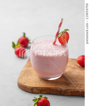 A glass of fresh strawberry smoothie on a wooden board on a light background with fresh berries. A glass of fresh strawberry smoothie on a wooden board on a light background with fresh berries. 119859709