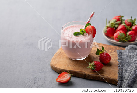 A glass of fresh strawberry smoothie with mint on a wooden board on a blue background A glass of fresh strawberry smoothie with mint on a wooden board on a blue background 119859720