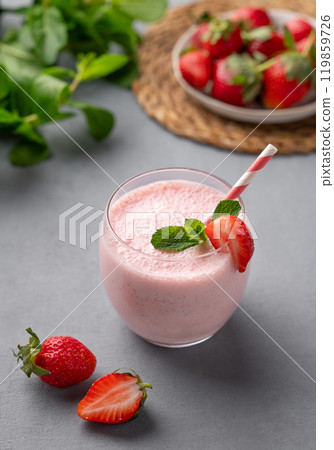 A glass of fresh strawberry smoothie on a blue background with fresh berries and mint. A glass of fresh strawberry smoothie on a blue background with fresh berries and mint. 119859726