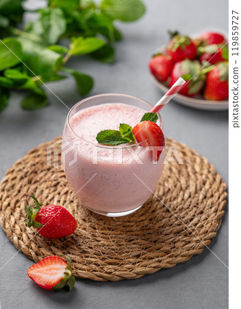 A glass of fresh strawberry smoothie with mint on a blue background with fresh berries. A glass of fresh strawberry smoothie with mint on a blue background with fresh berries. 119859727