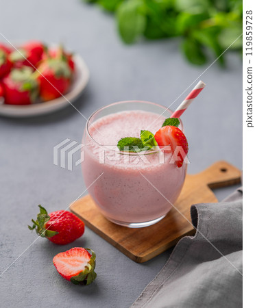 A glass of fresh strawberry smoothie with mint on a wooden board on a blue background A glass of fresh strawberry smoothie with mint on a wooden board on a blue background 119859728