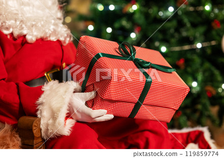 Festive image of Santa Claus in red suit with white beard holding red gift box with green ribbon Festive image of Santa Claus in red suit with white beard holding red gift box with green ribbon 119859774